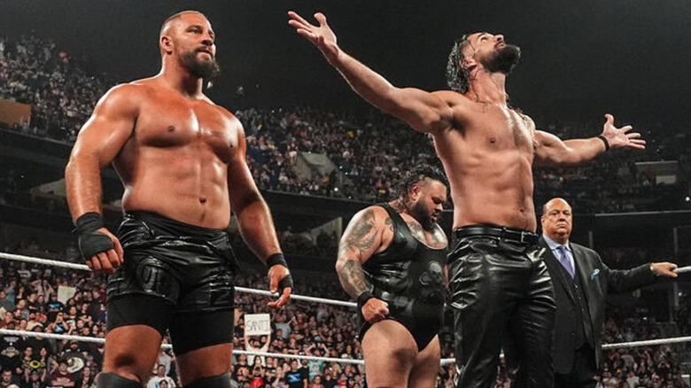 Bron Breakker alongside Seth Rollins, Bronson Reed, and Paul Heyman in ring.