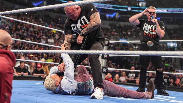 Randy Orton mauling Cody Rhodes with a steel chair while Pat McAfee talks on the mic during a 