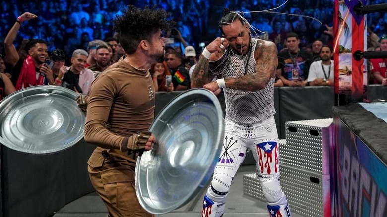 Rapper Bad Bunny looks to hit Damian Priest with trash can lids during their San Juan Street Fight at WWE Backlash 2023.