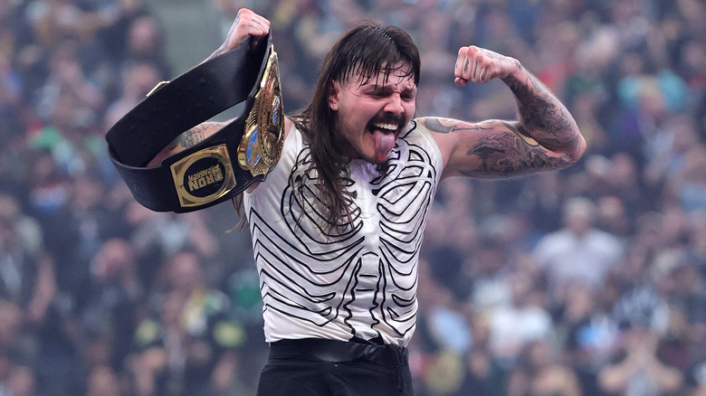 Dominik Mysterio holds the WWE Intercontinental Title high