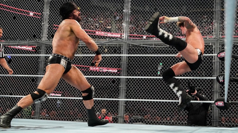 Drew McIntyre tosses CM Punk into the corner during their Hell in a Cell cage match in 2024