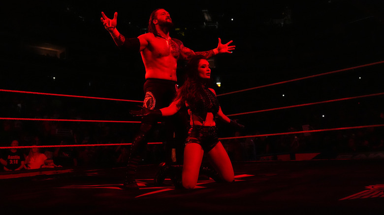 Karrion Kross, along with Scarlett, hit their signature pose before Kross competes in in-ring action