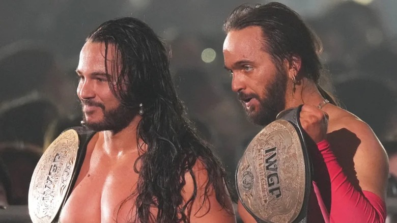 The Young Bucks posing with the IWGP Tag Team Championships during a New Japan Wrestling show.