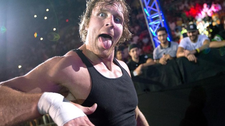 Dean Ambrose poses, tongue out, making a face, for WWE cameras during an entrance ahead of a match.