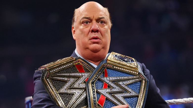 Paul Heyman holding a pair of title belts