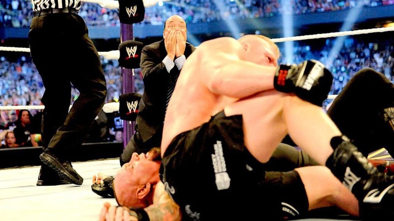 A shocked Paul Heyman looks on the background, as Brock Lesnar attempts to get to his feet following his pinfall victory over Brock Lesnar at WWE WrestleMania 30.