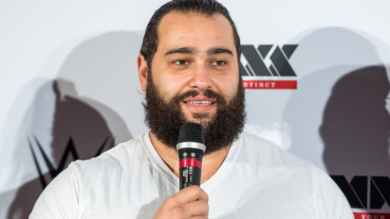 Rusev is holding a microphone