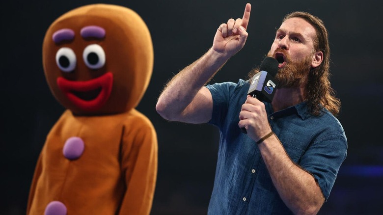 Sami Zayn cuts a promo in the ring, alongside a life-sized gingerbread man costume, during an episode of 