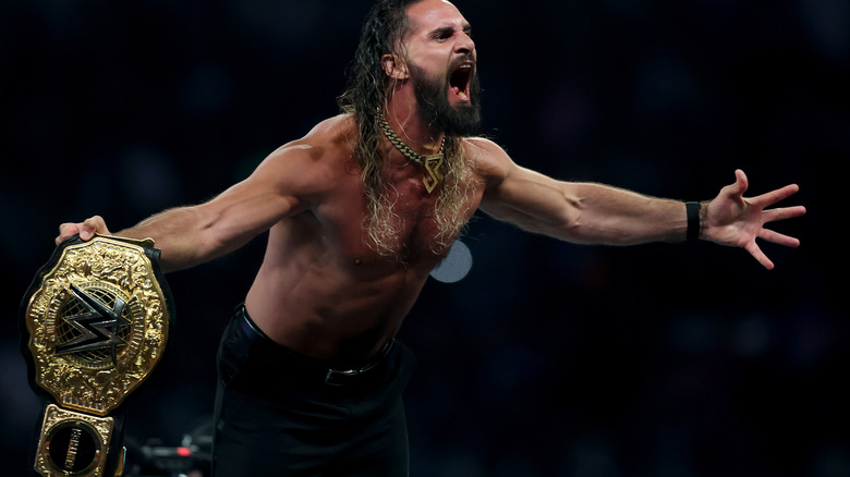 Seth Rollins screams and poses with World Heavyweight title in hand