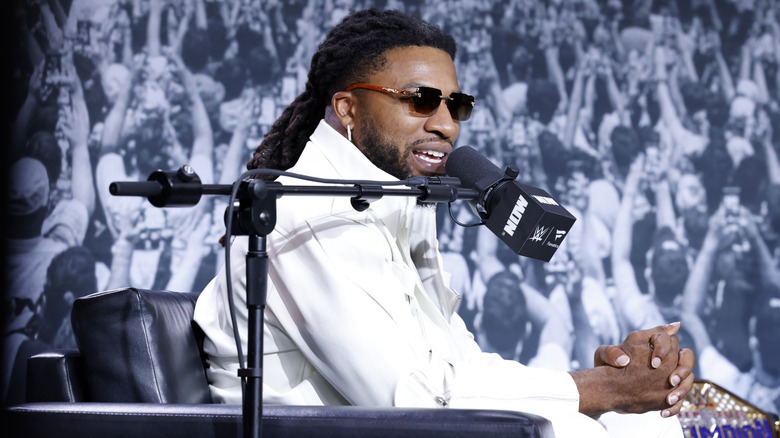 Trick Williams wearing a white suit and sunglasses at a press event