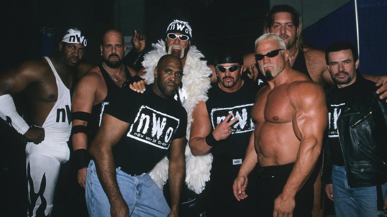 Members of the nWo (Stevie Ray, Scott Norton, Hollywood Hogan, Virgil, Buff Bagwell, The Giant, Scott Steiner, and Eric Bischoff) posing together backstage.