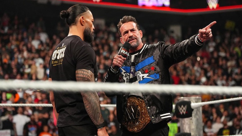 World Heavyweight Champion CM Punk points to the crowd while cutting a promo on Roman Reigns in the ring during an episode of 