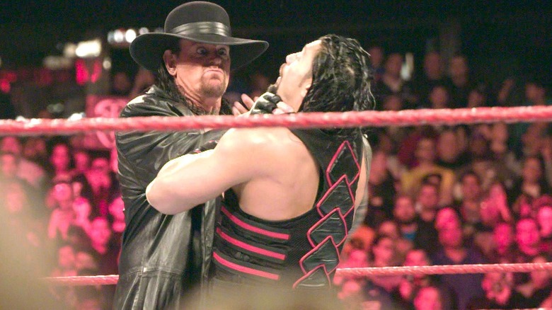 The Undertaker grasping Roman Reigns' neck for a Chokeslam.