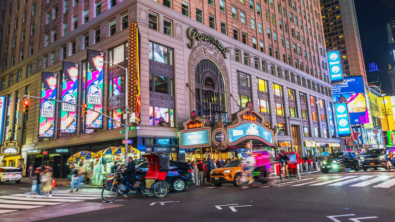 Hard Rock Cafe with iconic signage and illuminated Paramount Building at night in vibrant Times Square, New York City.