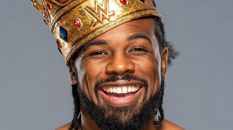 Xavier Woods smiles while wearing his King of the Ring crown