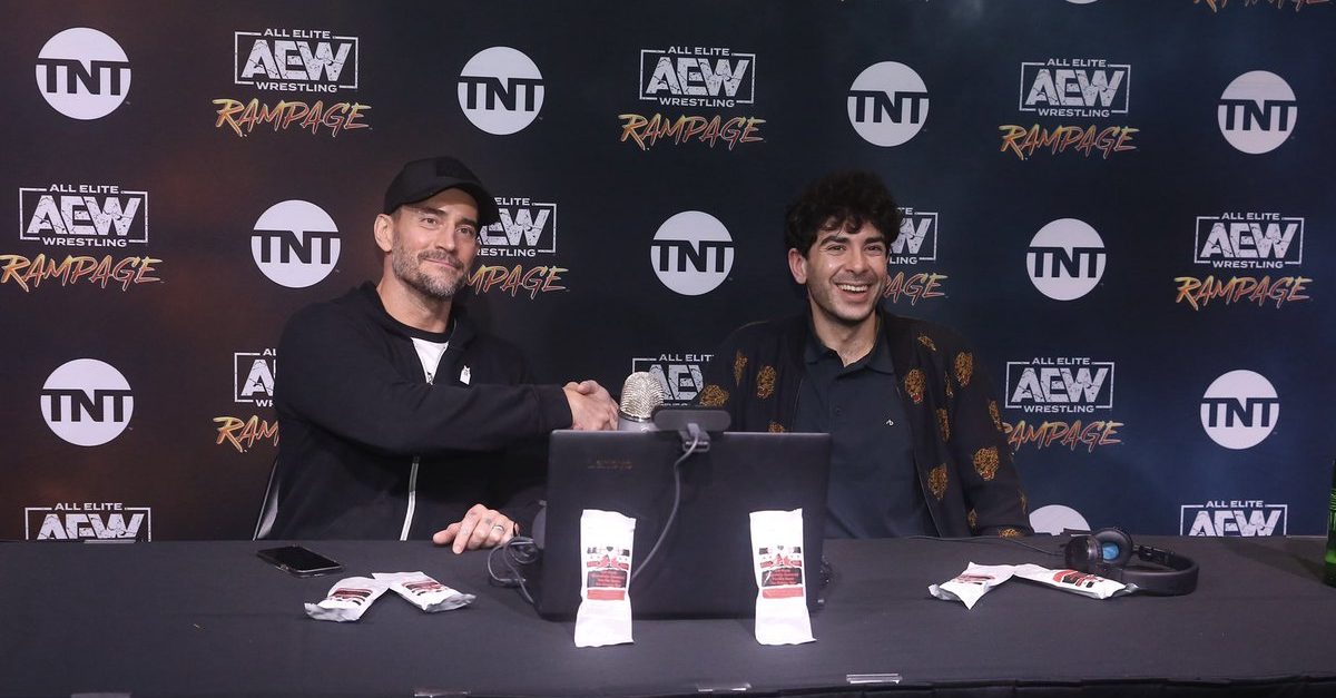 Tony Khan and CM Punk bumping fists during an AEW media scrum.